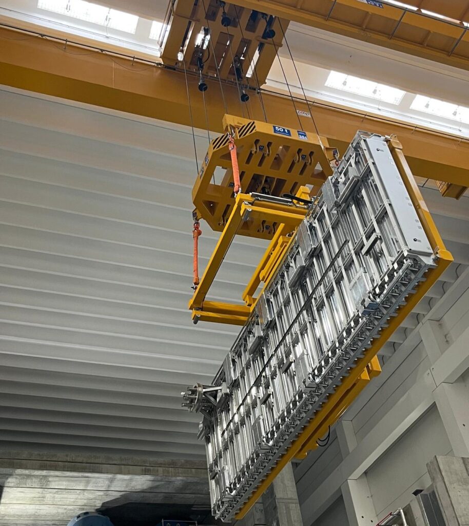 A crane transports one of the MITICA cryopump sections and the assembly tool towards the vessel. ©F4E