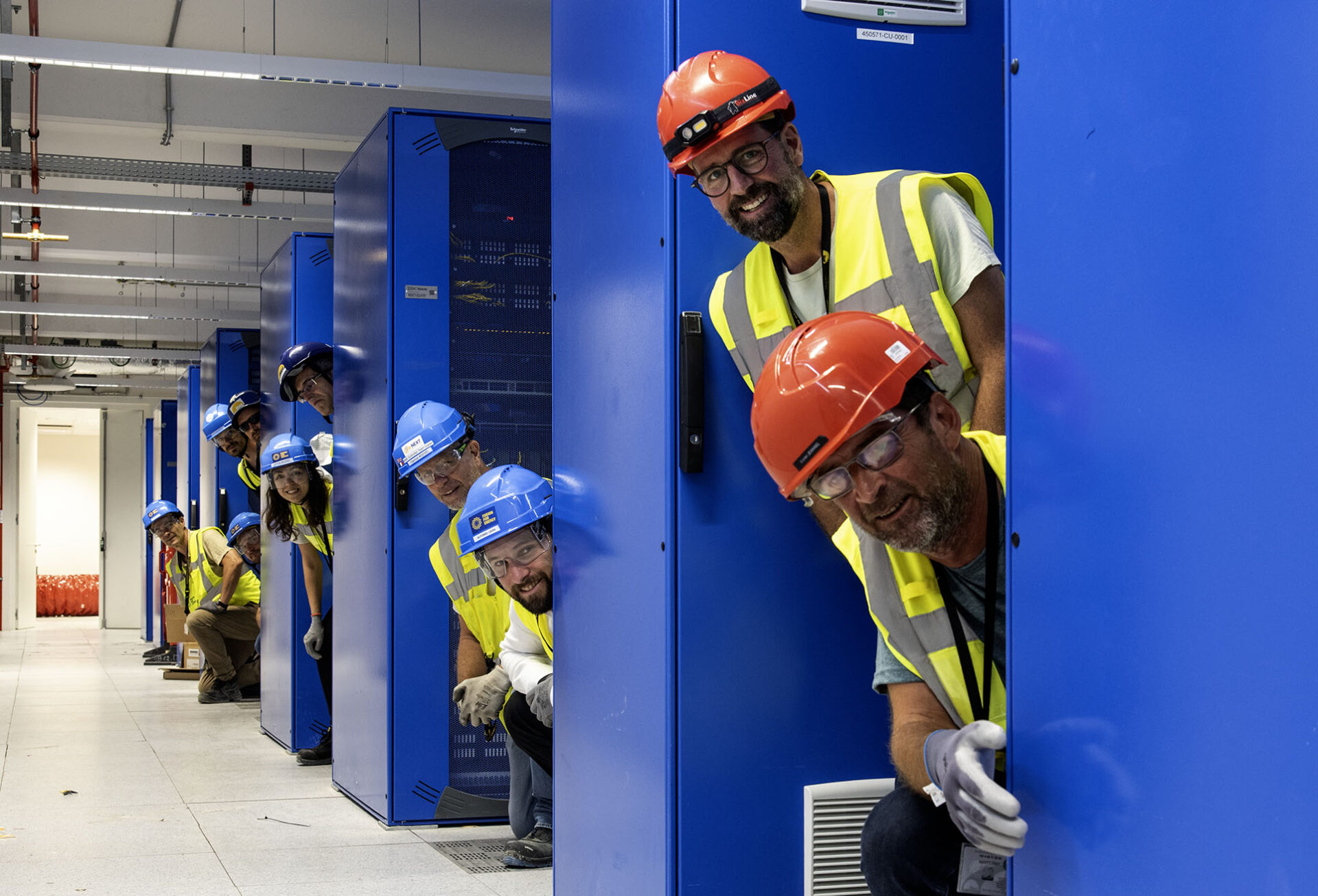 Colleagues from F4E, ITER Organization and Demathieu Bard peeking out from between the server racks, on the first floor of the Control Building. July 2025. 